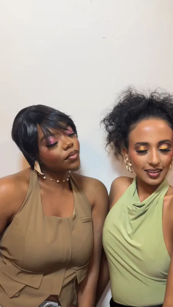 Two women side by side: one with pink eyeshadow, the other with golden eyeshadow and a flower earring